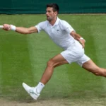 Novak Djokovic, tout vêtu de blanc, retour coup droit en bout de ligne sur le gazon de Wimbledon.