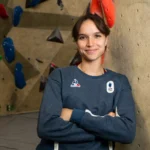 Oriane Bertone, les bras croisés devant un mur de bloc, pull bleu de l'équipe de France